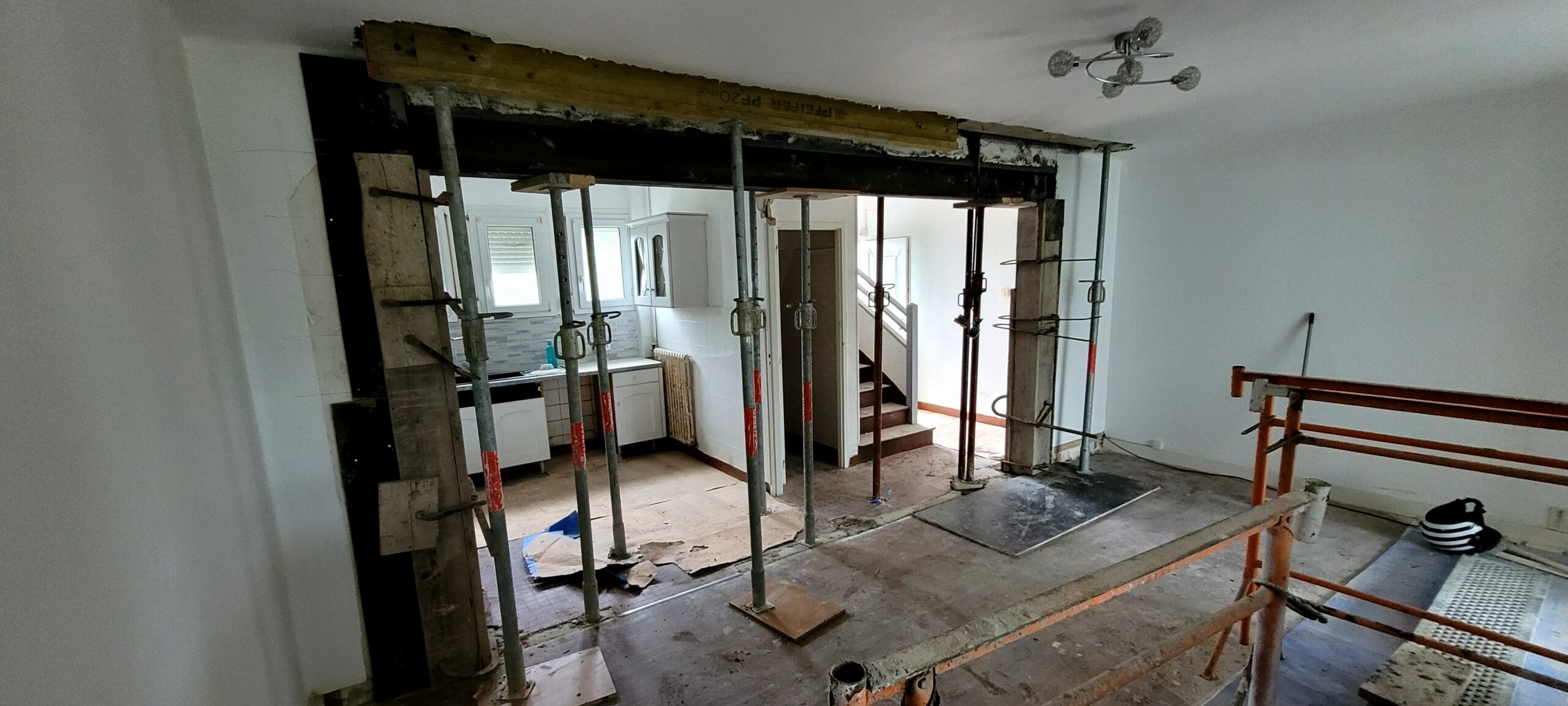 Chantier intérieur avec étais métalliques soutenant une poutre.