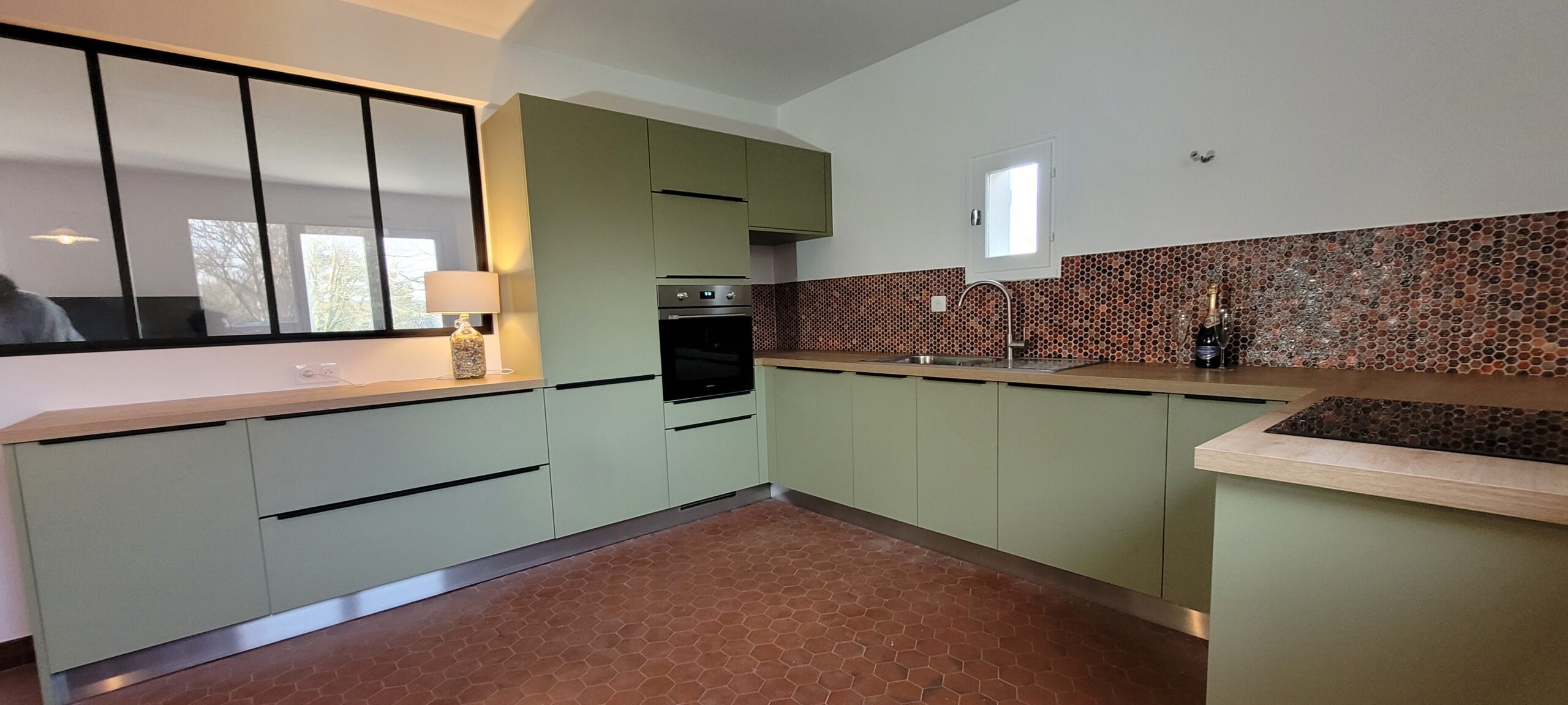 Cuisine moderne vert sauge avec sol en tomettes.