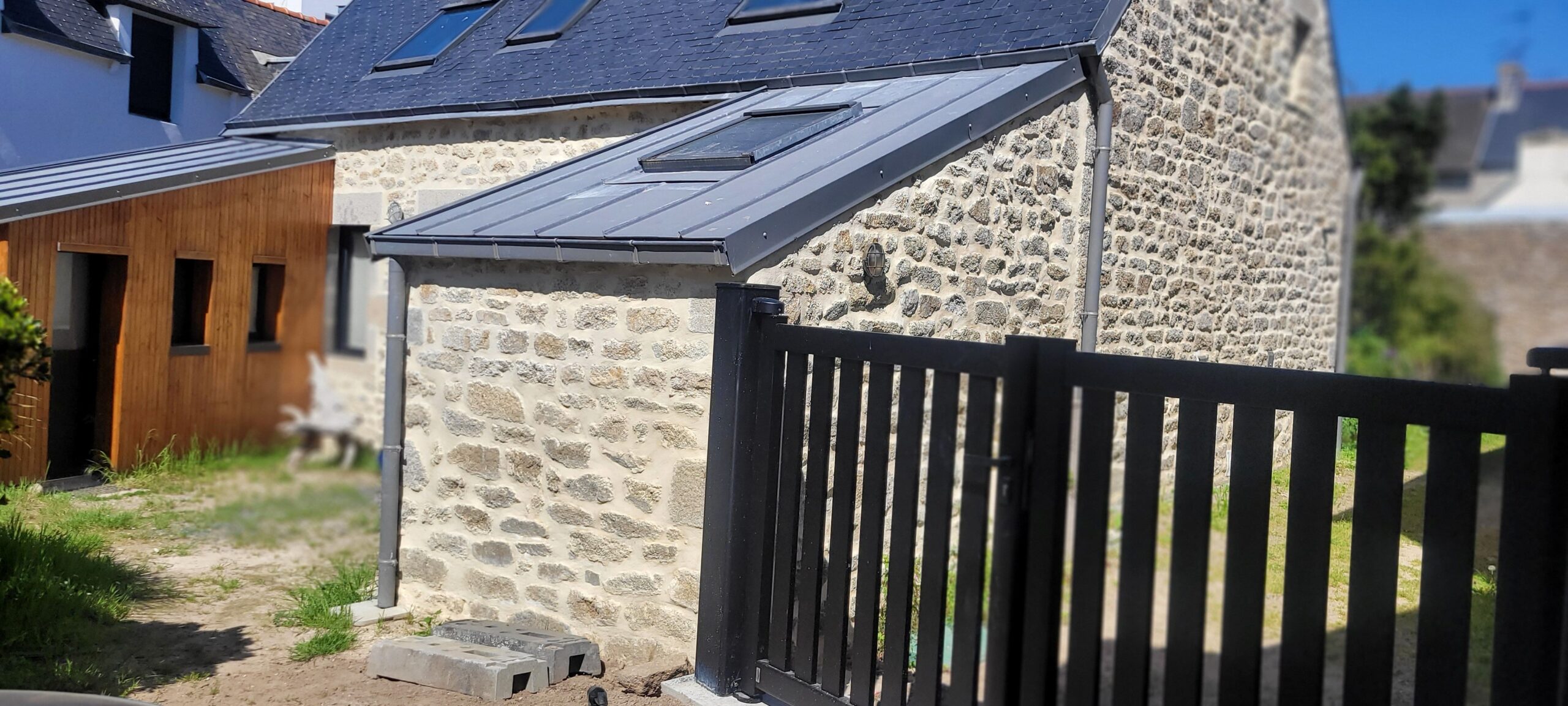 Maison en pierre avec extension moderne et toit anthracite.