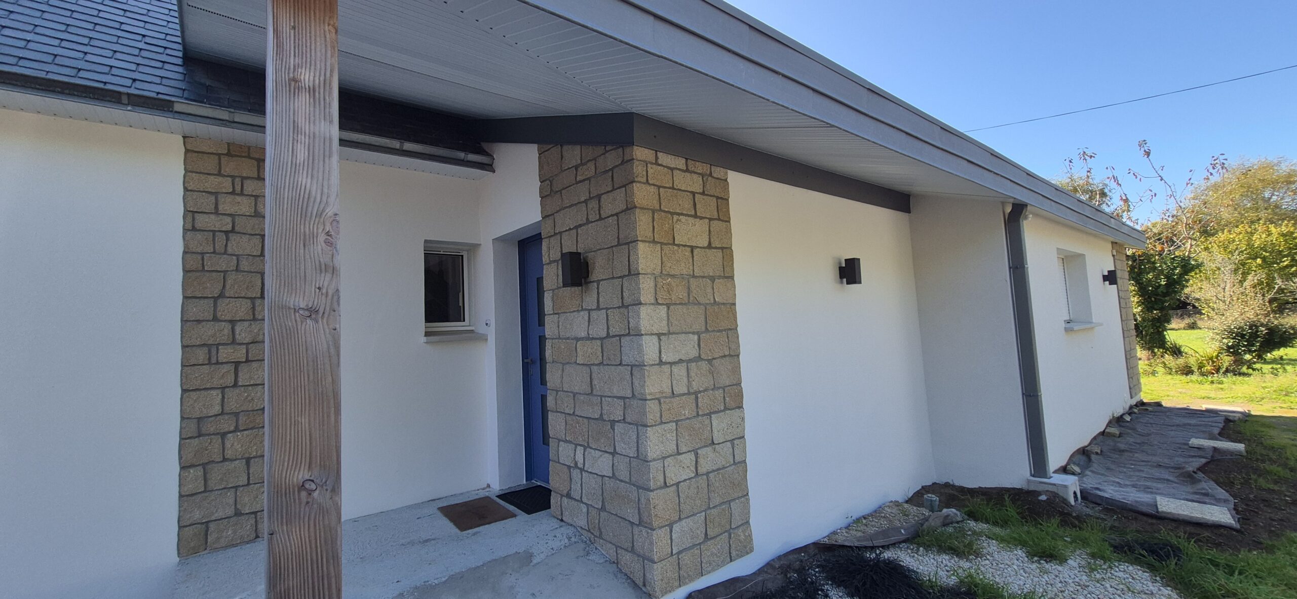 Entrée de maison moderne blanche avec colonnes en pierre.