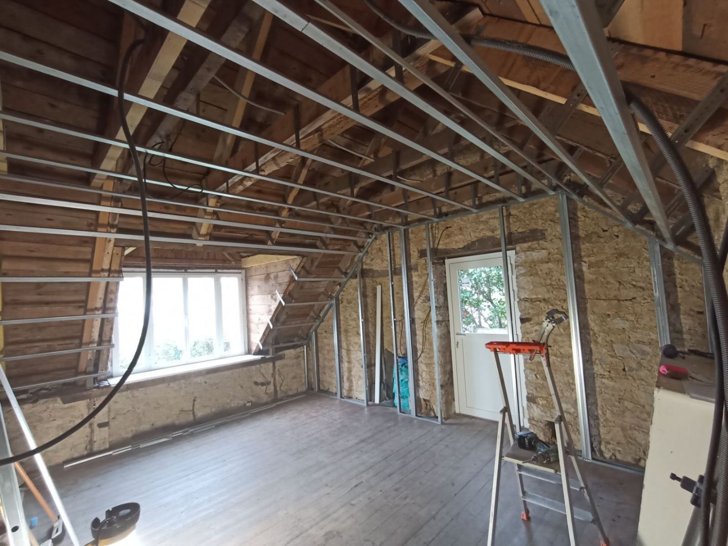 Pièce en rénovation avec ossature métallique et murs en pierre.