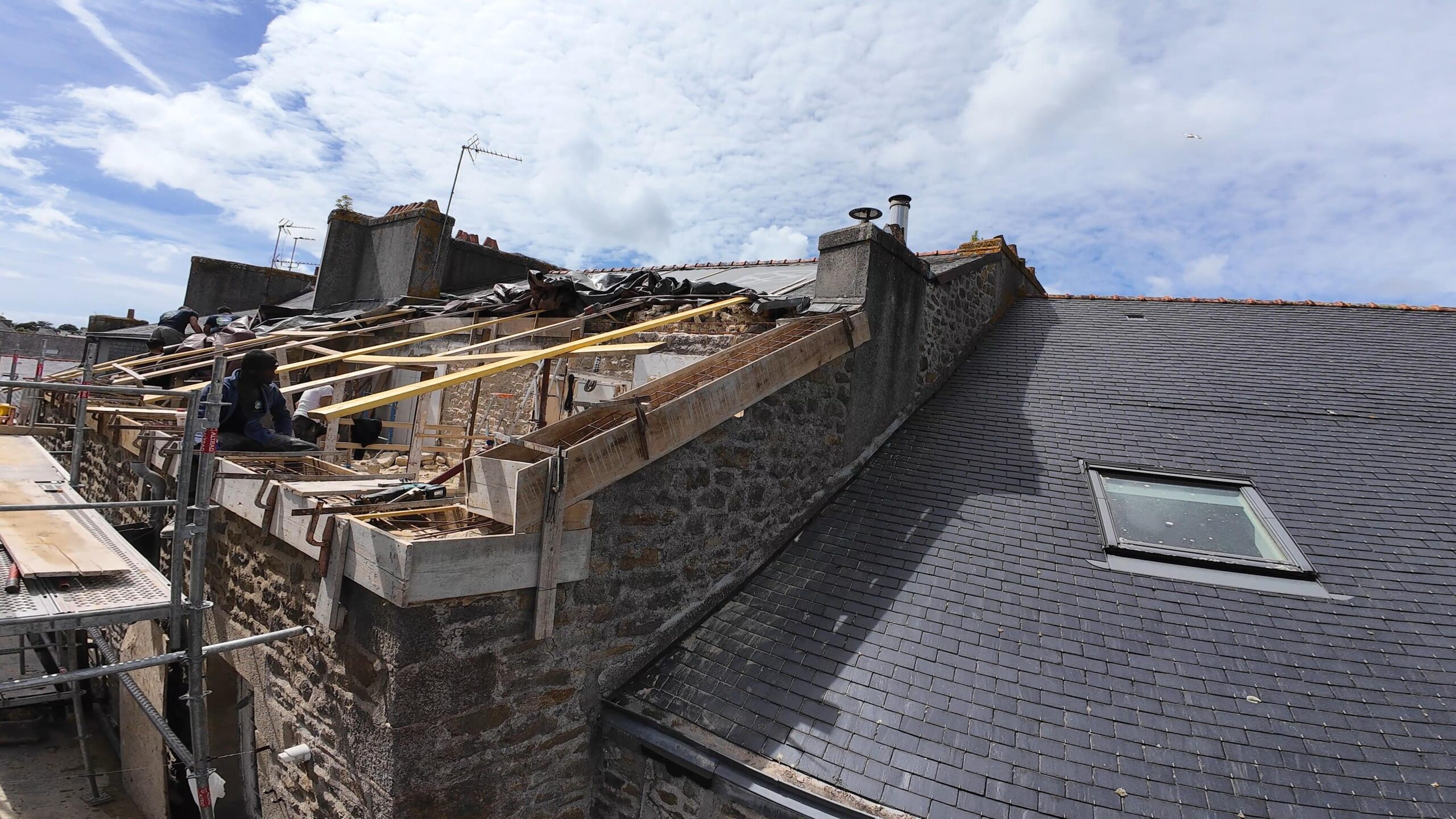 Travaux de rénovation de toiture sur une maison en pierre.